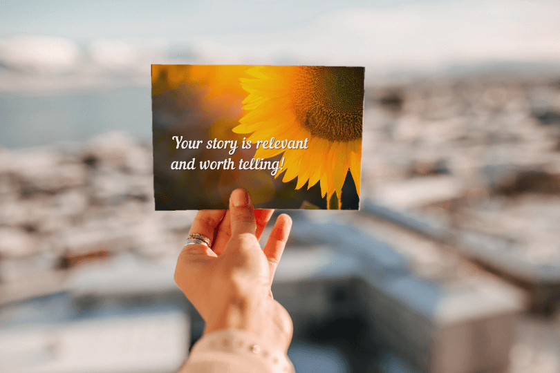 Hand holding a postcard of a sunflower with a white text that says "your story is relevant and worth telling"
